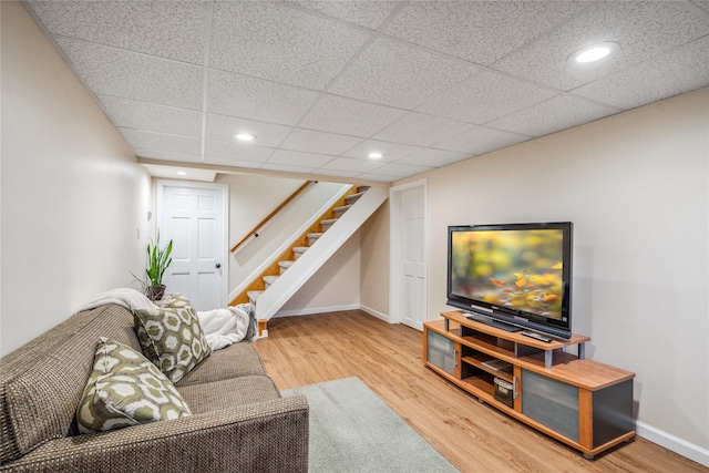 living room featuring wood-type flooring and a drop ceiling