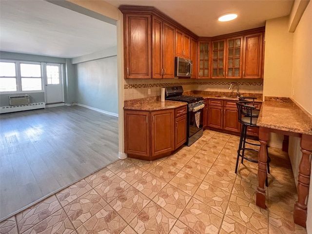 kitchen with sink, tasteful backsplash, light wood-type flooring, appliances with stainless steel finishes, and light stone countertops