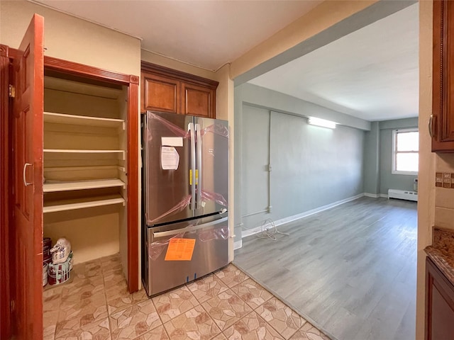 kitchen with stainless steel refrigerator, a baseboard radiator, and light hardwood / wood-style flooring