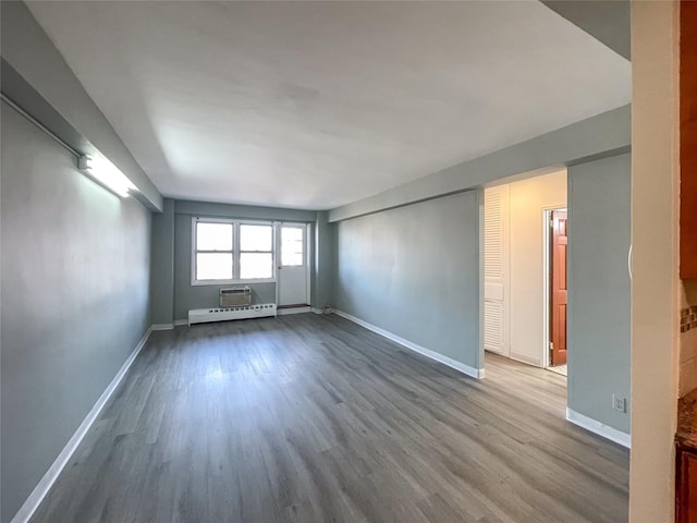 unfurnished room featuring hardwood / wood-style flooring and a baseboard radiator