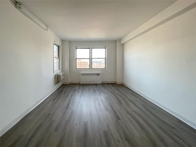 empty room featuring dark hardwood / wood-style flooring, radiator heating unit, and a wall mounted AC