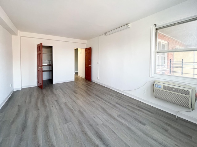 unfurnished bedroom featuring hardwood / wood-style floors and an AC wall unit