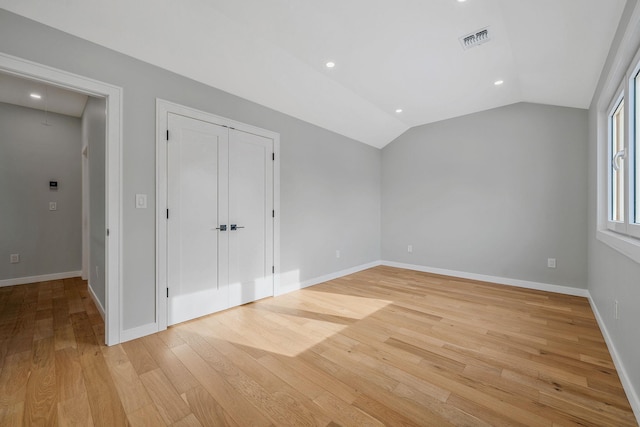 unfurnished bedroom with lofted ceiling and light hardwood / wood-style flooring