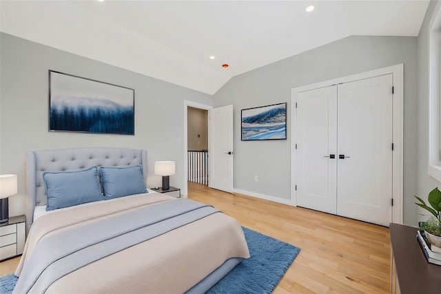 bedroom featuring hardwood / wood-style flooring, lofted ceiling, and a closet