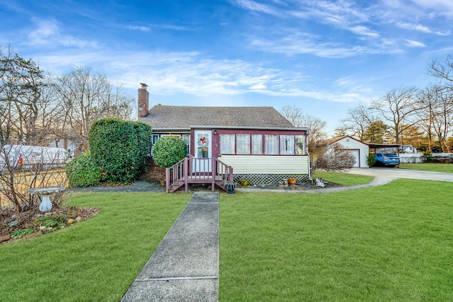 view of front of house featuring a garage, an outdoor structure, and a front lawn