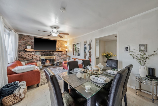 tiled dining area featuring crown molding, brick wall, ceiling fan, and a fireplace