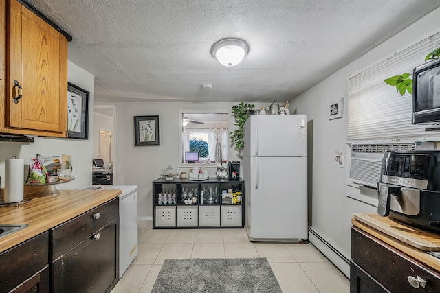 kitchen featuring white refrigerator, light tile patterned flooring, a textured ceiling, and a baseboard heating unit