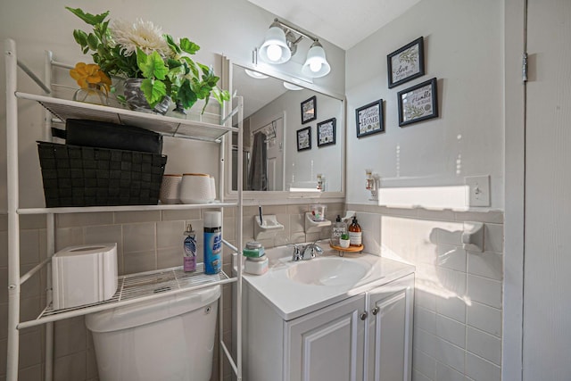 bathroom with tasteful backsplash, vanity, toilet, and tile walls