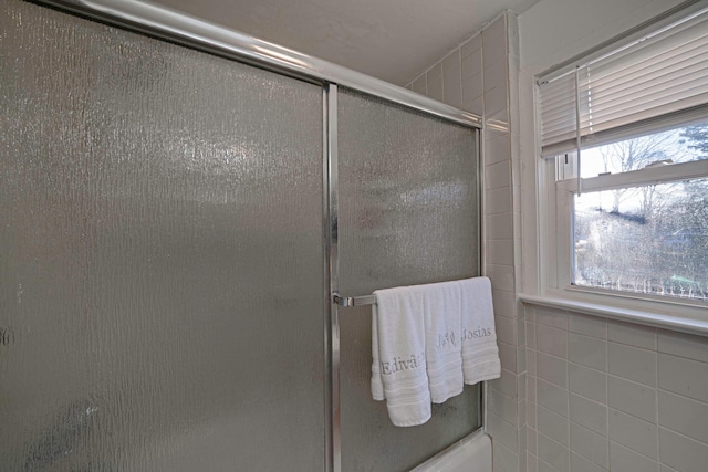 bathroom with bath / shower combo with glass door