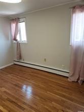 spare room with baseboard heating and dark wood-type flooring