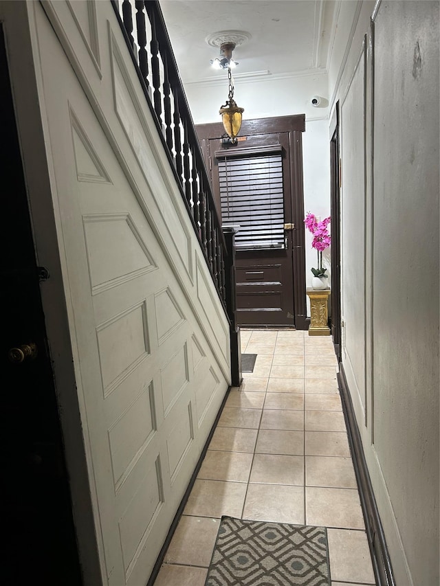 hall with ornamental molding and light tile patterned flooring