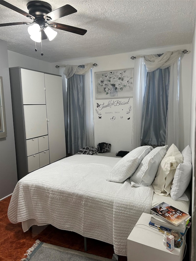 bedroom with dark hardwood / wood-style flooring, a textured ceiling, and ceiling fan