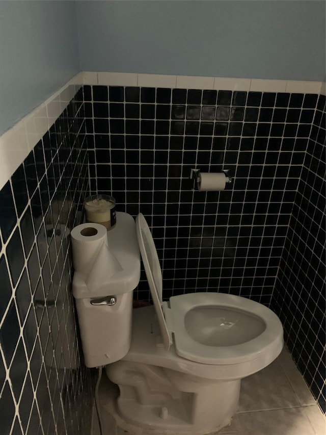 bathroom featuring tile patterned flooring, tile walls, and toilet