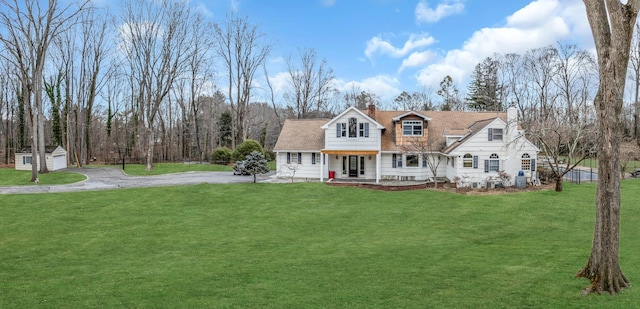 new england style home featuring a front lawn and a storage unit