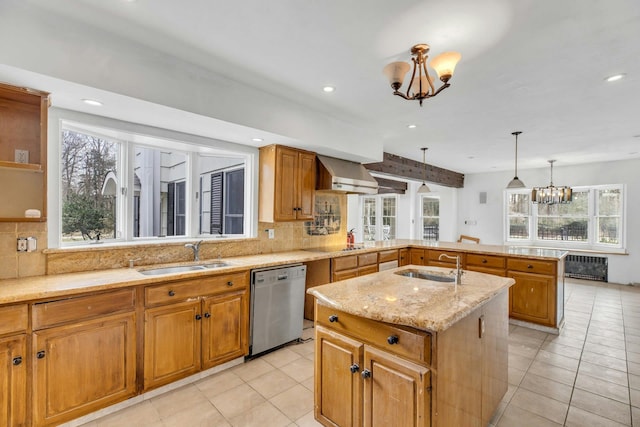 kitchen featuring wall chimney range hood, dishwasher, a kitchen island with sink, and sink