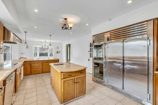 kitchen with light tile patterned floors, sink, appliances with stainless steel finishes, hanging light fixtures, and a center island with sink