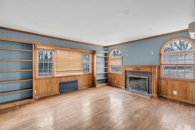 unfurnished living room featuring radiator, hardwood / wood-style flooring, a fireplace, and ornamental molding