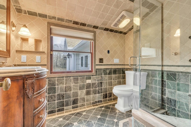 bathroom with walk in shower, tile patterned floors, toilet, tile walls, and vanity