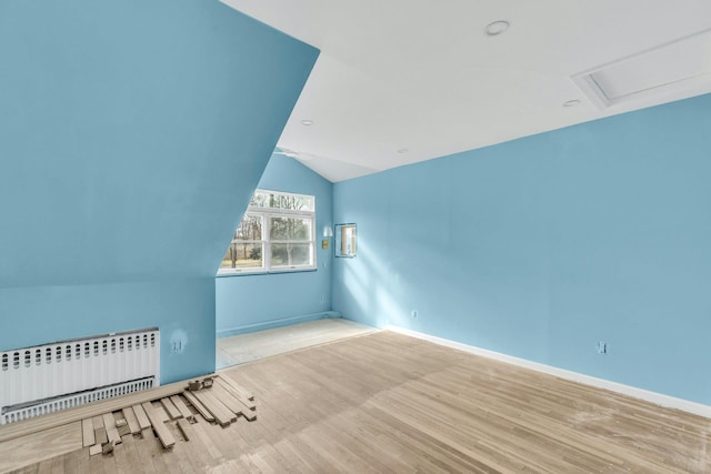 bonus room featuring lofted ceiling, radiator heating unit, and light wood-type flooring