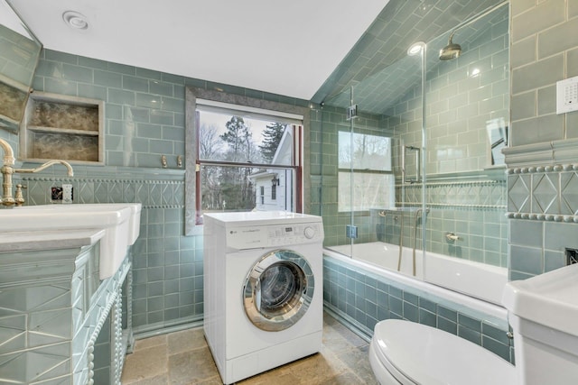 full bathroom featuring lofted ceiling, tile walls, tiled shower / bath combo, vanity, and washer / dryer