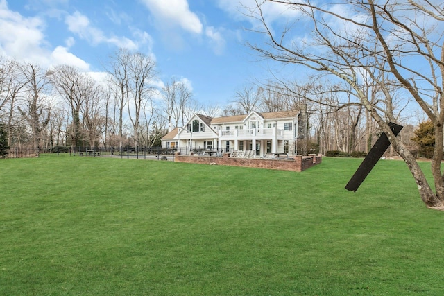 back of house featuring a balcony, covered porch, and a lawn