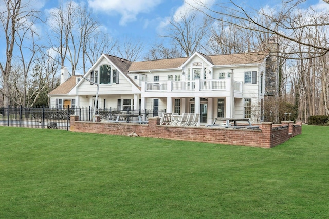 rear view of house featuring a balcony, a patio, and a lawn