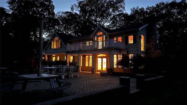 back house at dusk with a balcony and a patio area