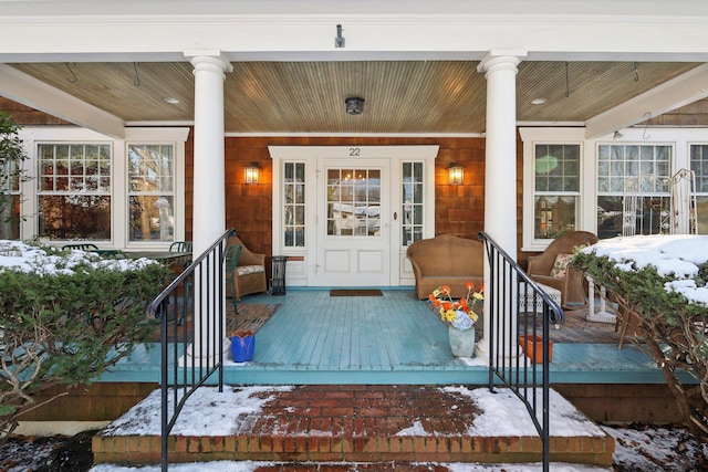 snow covered property entrance with covered porch