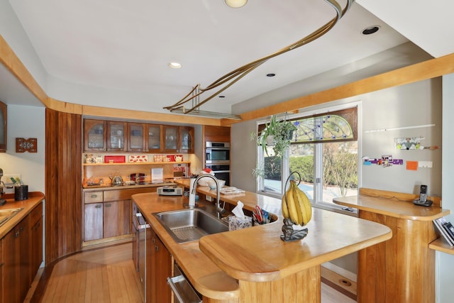 kitchen with sink, light hardwood / wood-style flooring, an island with sink, and appliances with stainless steel finishes