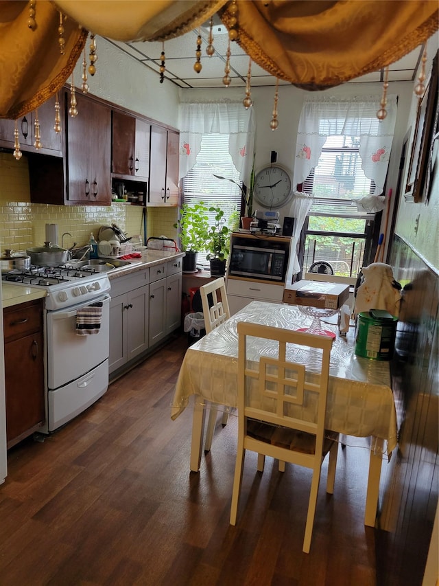 kitchen with dark wood-type flooring, dark brown cabinetry, sink, tasteful backsplash, and white range with gas cooktop