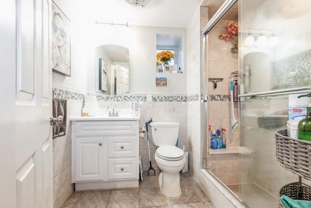 bathroom featuring vanity, toilet, tile walls, and walk in shower