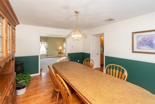 dining space with hardwood / wood-style floors, a notable chandelier, and baseboard heating