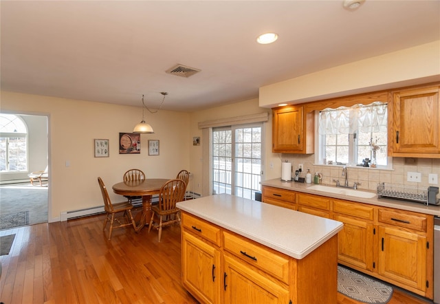 kitchen with sink, decorative light fixtures, a center island, a baseboard radiator, and decorative backsplash