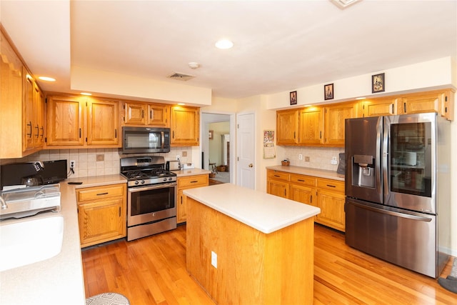 kitchen with stainless steel appliances, a center island, sink, and light hardwood / wood-style floors