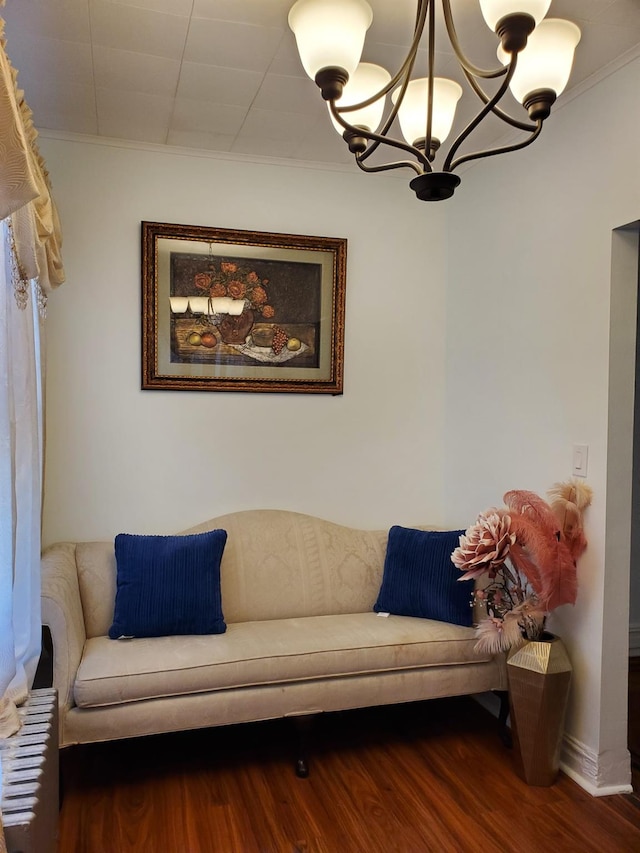 living area featuring an inviting chandelier, crown molding, and dark hardwood / wood-style flooring