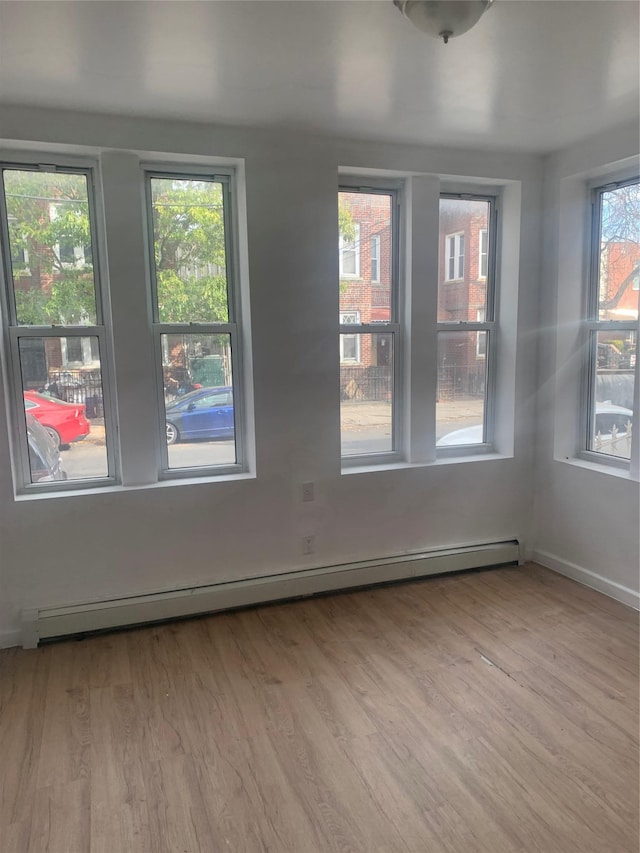 spare room featuring a baseboard radiator and light wood-type flooring