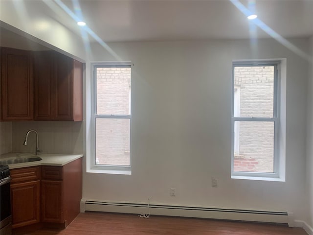 kitchen featuring a baseboard radiator, sink, and light hardwood / wood-style flooring