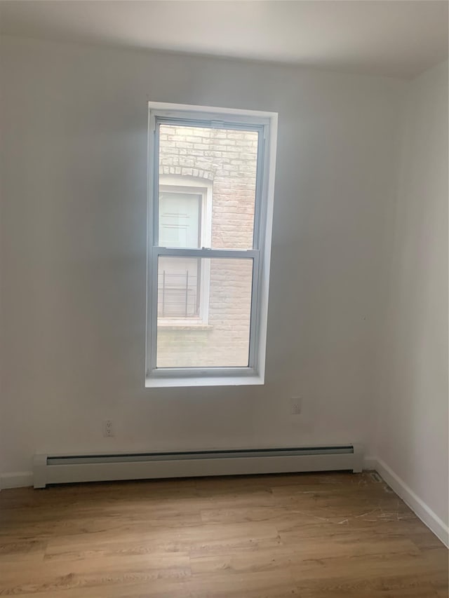 empty room with light hardwood / wood-style floors and a baseboard heating unit