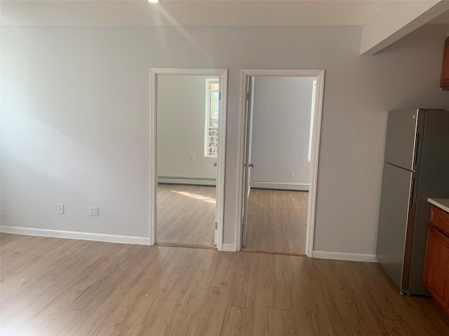 kitchen featuring baseboard heating, stainless steel fridge, and light hardwood / wood-style flooring