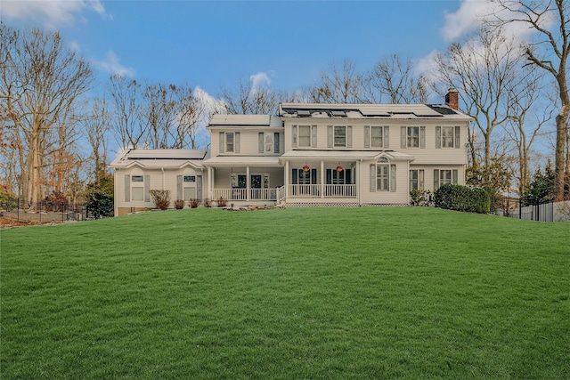 rear view of house with a lawn, solar panels, and covered porch