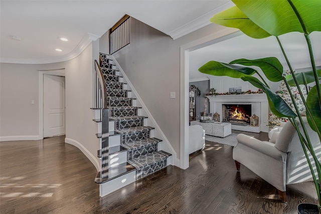 stairs featuring a brick fireplace, hardwood / wood-style flooring, and ornamental molding