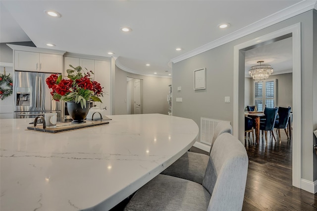 kitchen with white cabinetry, crown molding, a kitchen bar, stainless steel refrigerator with ice dispenser, and dark wood-type flooring