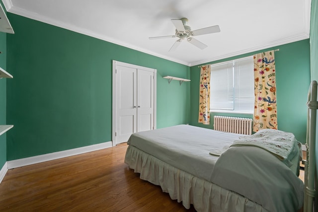 bedroom featuring radiator heating unit, wood-type flooring, ceiling fan, crown molding, and a closet