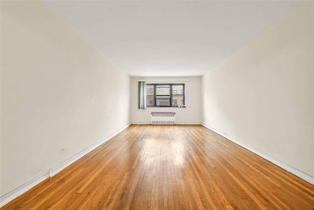 spare room with cooling unit, radiator heating unit, and light hardwood / wood-style floors