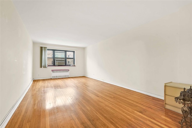 spare room featuring radiator and light hardwood / wood-style floors