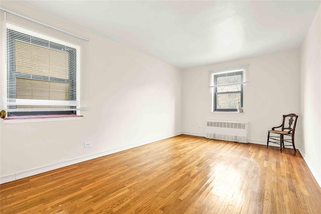 spare room featuring radiator heating unit and light wood-type flooring