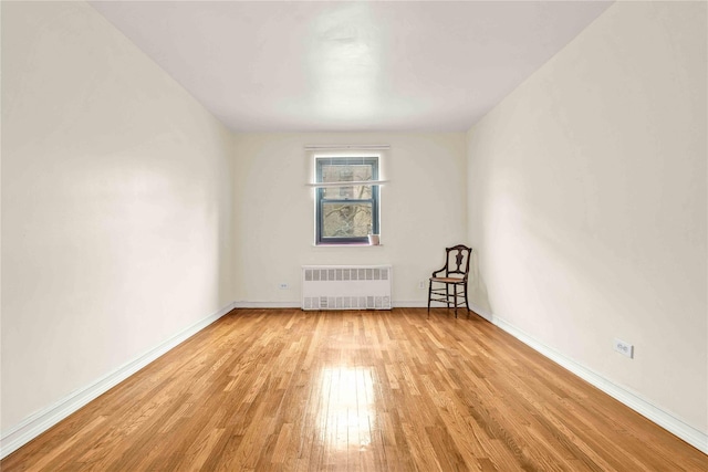 unfurnished room with radiator heating unit and light wood-type flooring