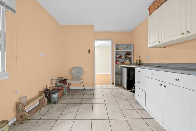 kitchen featuring fridge, light tile patterned floors, and white cabinets