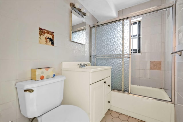 full bathroom with vanity, combined bath / shower with glass door, tile walls, and toilet