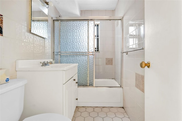 full bathroom featuring enclosed tub / shower combo, vanity, toilet, and tile walls